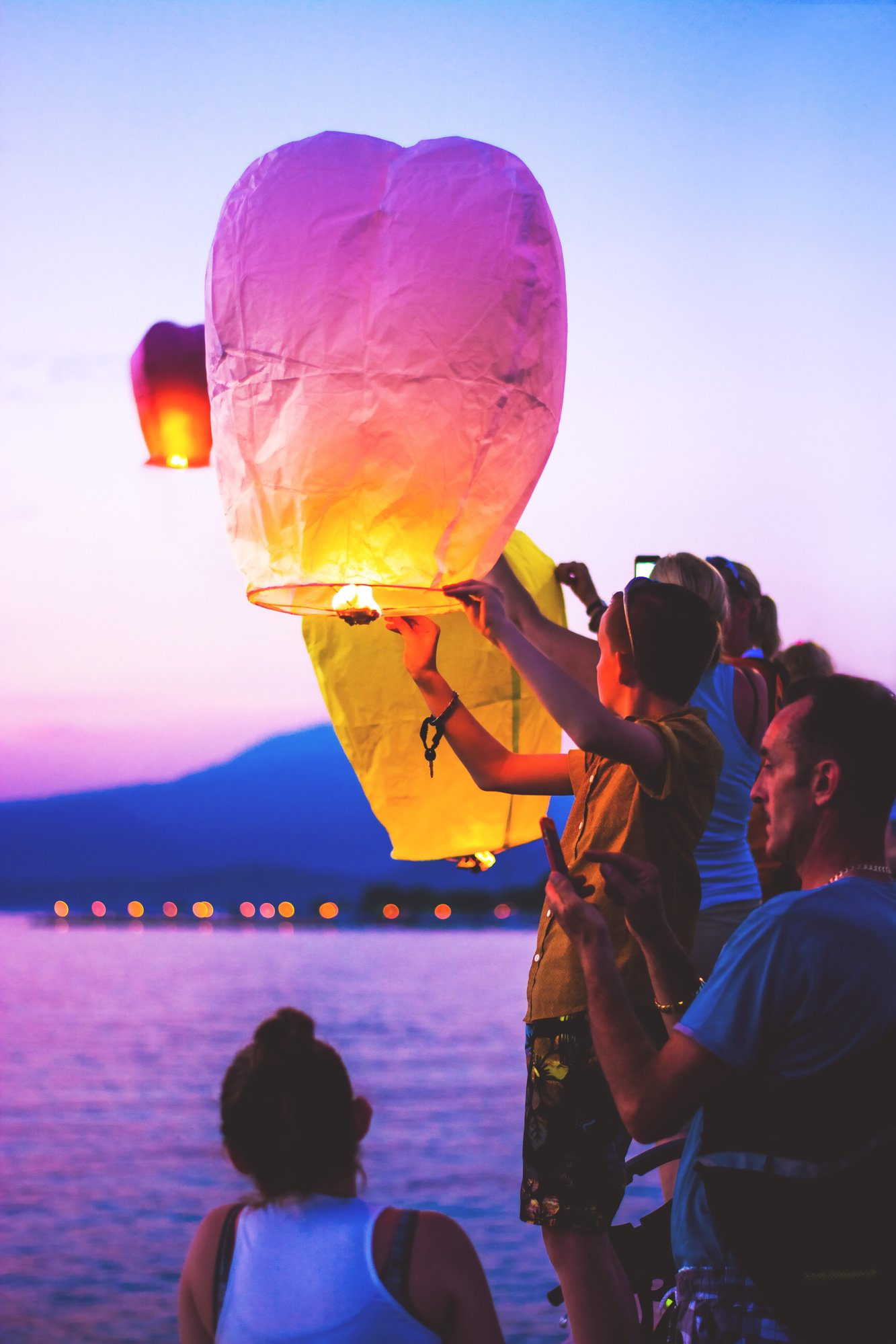 Family releasing lanterns into sky at sunset